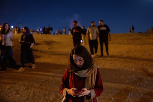 A protestor holding a phone in the dark during a demonstration in Iran