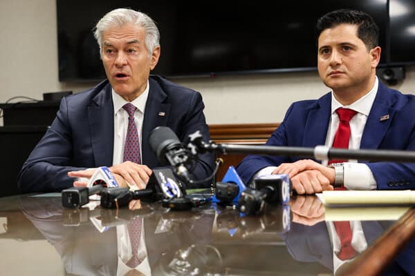 Dr. Mehmet Oz speaking to reporters during a visit to a California healthcare facility, flanked by federal agents