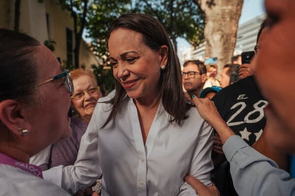 Maria Corina Machado speaking at a podium with a Nobel Prize insignia in the background