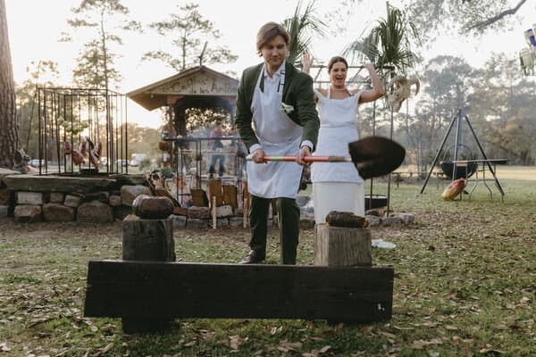 A chef cooking meat over an open fire pit at an outdoor wedding reception